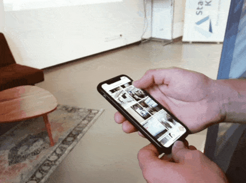 Gast scrollt auf dem Smartphone durch den laufenden imiji Livestream, im Hintergrund die Leinwand